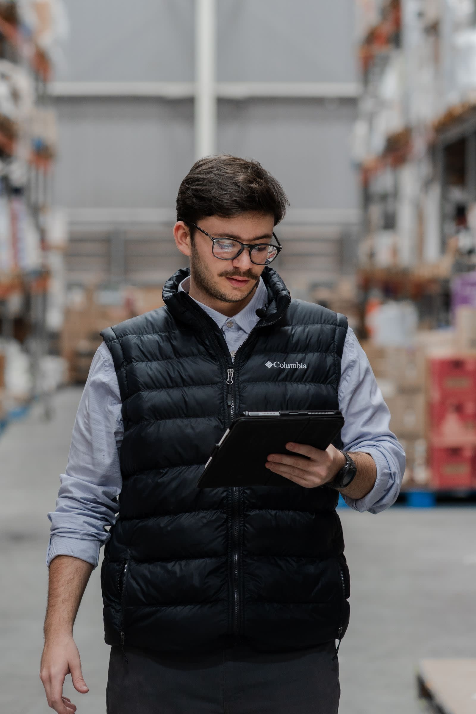 Skladník s tabletem kontroluje zásoby v regálovém skladu
