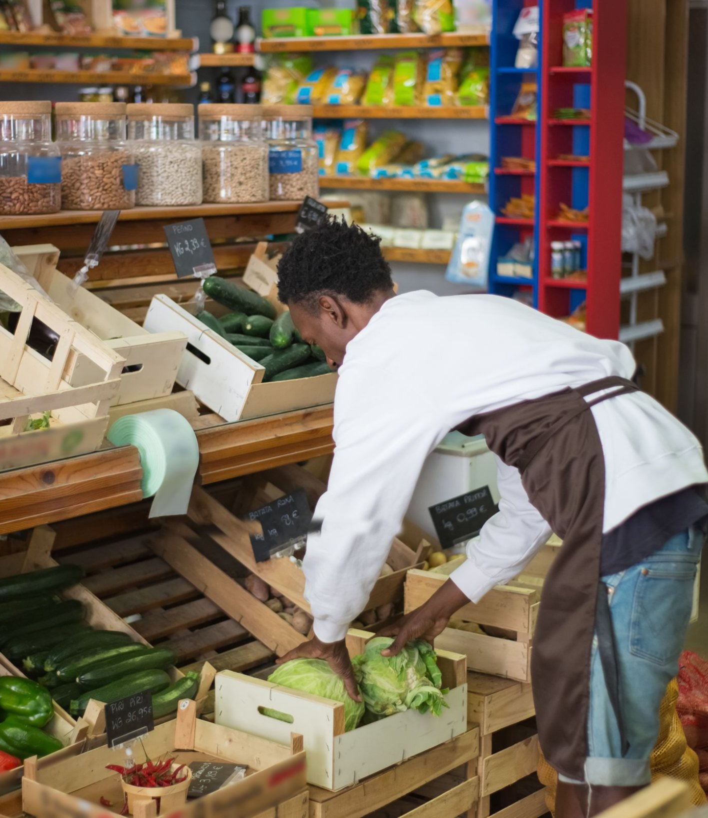Store employee arranging fresh vegetables on a produce shelf
