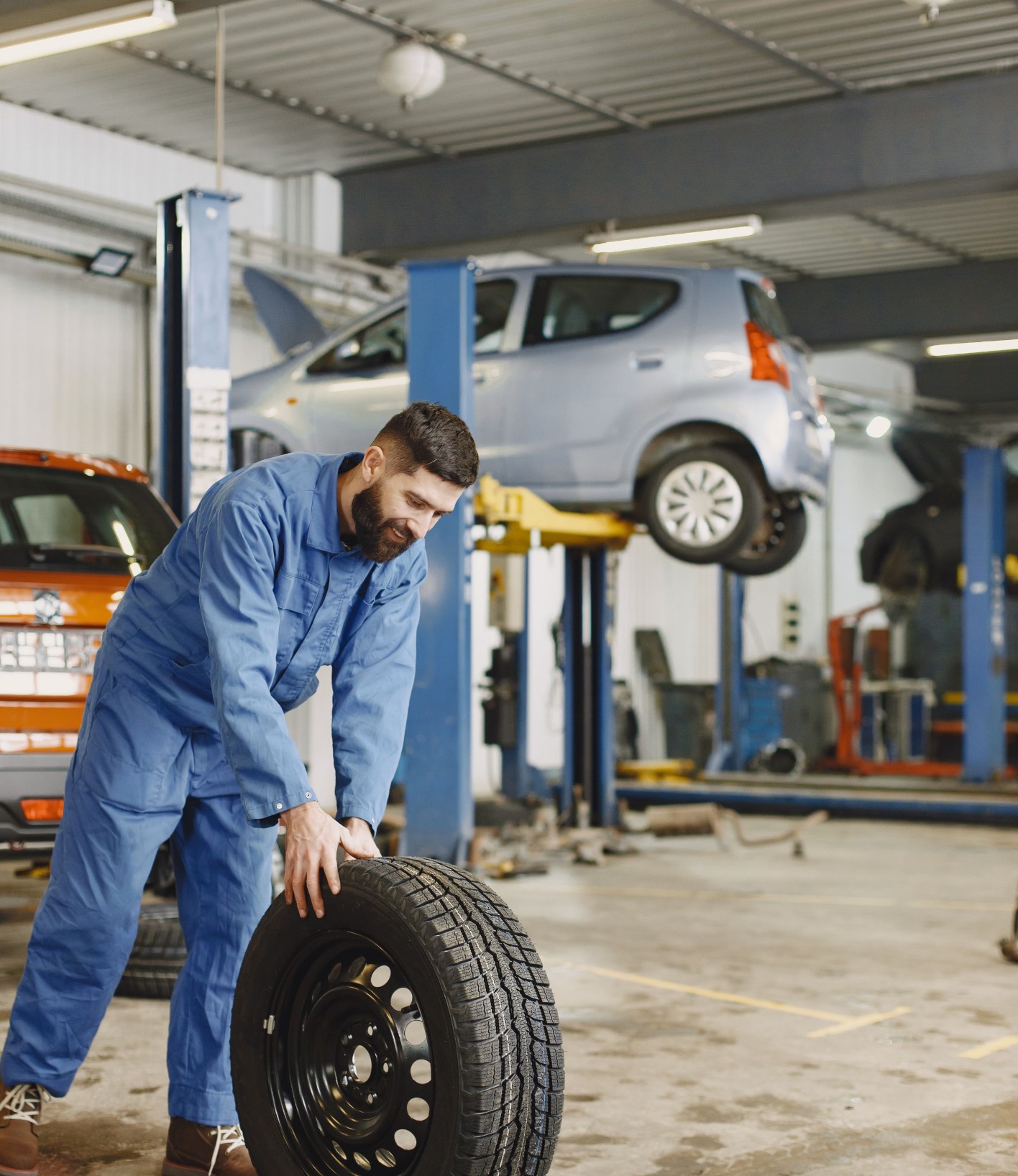 Mechanic with a tyre in a car workshop